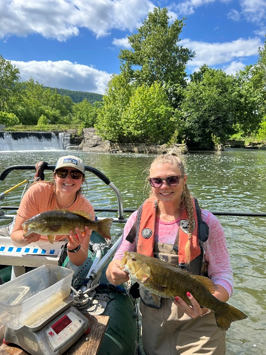 Two anglers on a boat holding fish on the North Fork Shenandoah River.