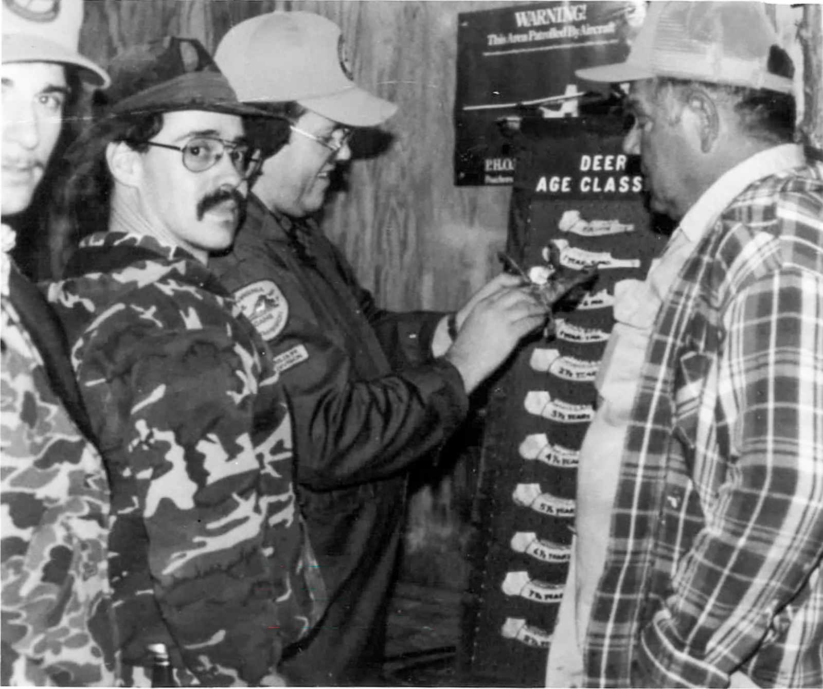 አዳኞች የአጋዘን መንጋጋ አጥንትን ሲለኩ የሚያሳይ አሮጌ ጥቁር እና ነጭ ምስል።