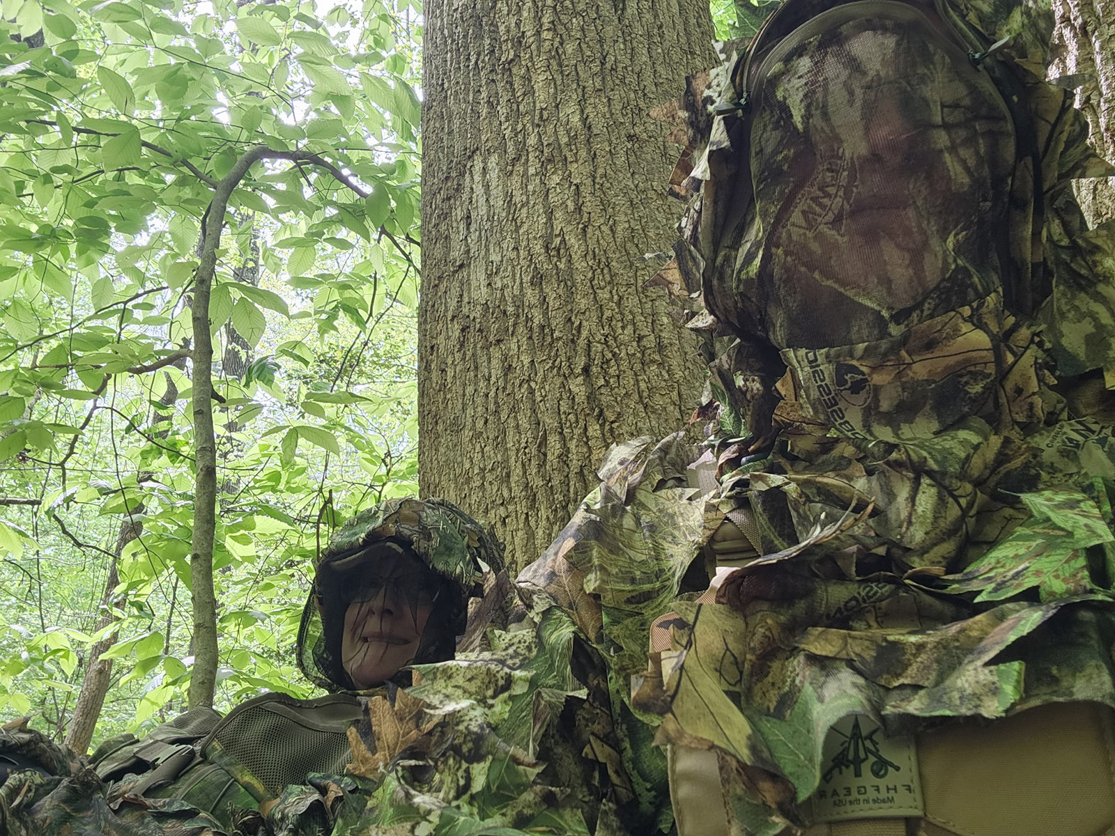 በጫካ ውስጥ ካሜራ (camouflage) እና የፊት መሸፈኛ የለበሱ ሁለት ሴቶች ፎቶ።