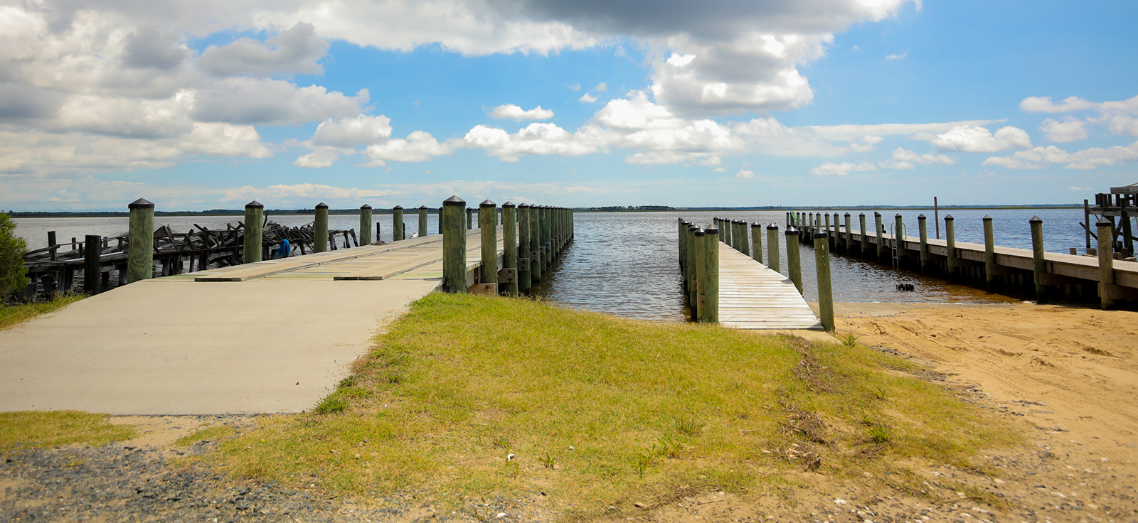 በቀኝ በኩል ያለው የጀልባ መወጣጫ እና በግራ በኩል ያለው የመትከያ ቦታ ወደ ውሃው ውስጥ የሚዘረጋ ፎቶ።